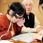 眼鏡に取り付けた視覚支援機器で、新聞の読み取りを体験する参加者＝丹波篠山市、丹南健康福祉センター