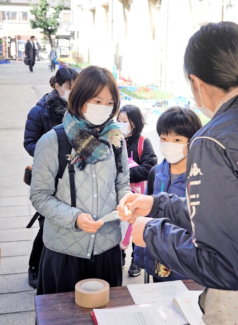 体温などを記入した登校予定表を提出する保護者や児童ら＝３日午前８時２０分、尼崎市三反田町２、市立立花南小学校
