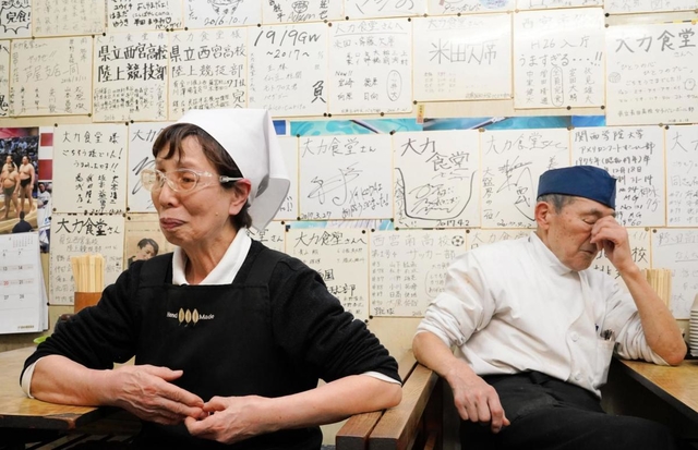 大会の中止を知り、肩を落とす藤坂悦夫さん（右）と初枝さん。壁は、かつて提供していた大盛りのカツ丼を完食した球児らの色紙で埋まる＝１１日午後６時１９分、西宮市甲子園網引町、大力食堂