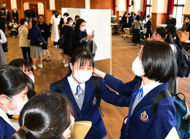 分散して掲示された受験番号から、自分の番号を見つけて喜ぶ受験生ら＝神戸市灘区城の下通１（撮影・秋山亮太）