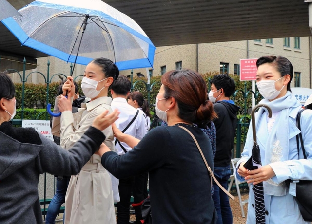 声楽教室の先生と喜びを分かち合い、学校へ向かうマスク姿の合格者＝２７日午前、宝塚市武庫川町