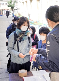 体温などを記入した登校予定表を提出する保護者や児童ら＝３日午前８時２０分、尼崎市三反田町２、市立立花南小学校