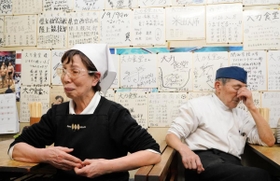 大会の中止を知り、肩を落とす藤坂悦夫さん（右）と初枝さん。壁は、かつて提供していた大盛りのカツ丼を完食した球児らの色紙で埋まる＝１１日午後６時１９分、西宮市甲子園網引町、大力食堂