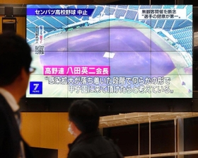 明石商高の地元で、センバツ中止のテレビニュースに見入る人たち＝１１日夜、明石市大明石町１