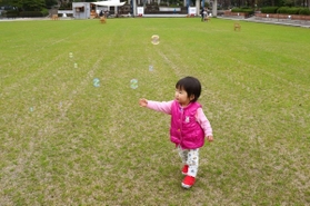 養生が終わり開放された芝生広場で、シャボン玉を飛ばして遊ぶ子ども＝１４日午後、神戸市中央区加納町６、東遊園地（撮影・吉田敦史）