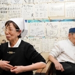 大会の中止を知り、肩を落とす藤坂悦夫さん（右）と初枝さん。壁は、かつて提供していた大盛りのカツ丼を完食した球児らの色紙で埋まる＝１１日午後６時１９分、西宮市甲子園網引町、大力食堂