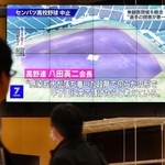 明石商高の地元で、センバツ中止のテレビニュースに見入る人たち＝１１日夜、明石市大明石町１