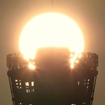 オレンジ色の夕日と重なった神戸ポートタワー＝神戸市中央区新港町から