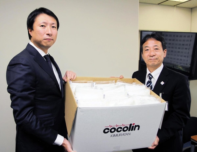 神戸市の山村昭こども家庭局長（右）にマスクを寄贈するキムラタンの清川浩志社長＝神戸市役所