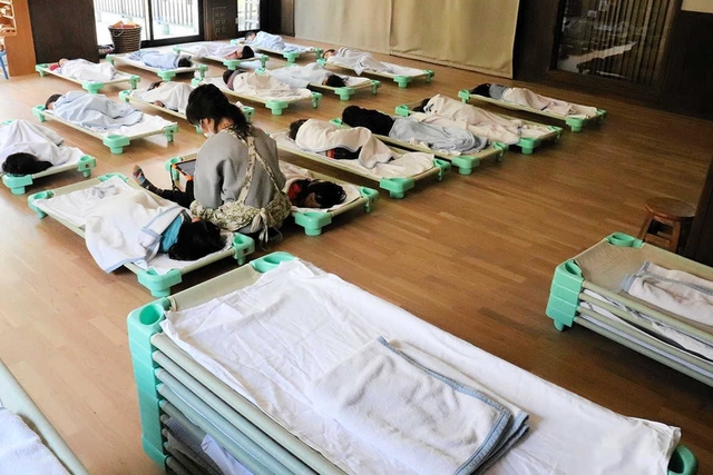 園に通う子どもが減り、昼寝の部屋もまばら。手前には使われないベッドが積まれている＝９日、神戸市垂水区名谷町