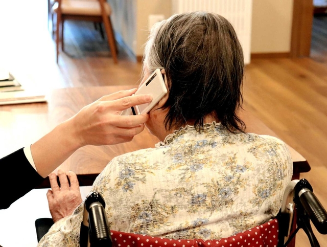 施設の携帯電話で家族と通話する入所者。面会できない寂しさを和らげる＝神戸市垂水区名谷町、特別養護老人ホーム「花の森」