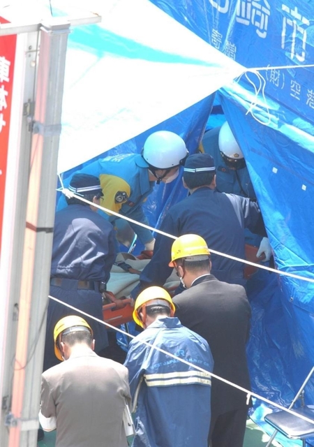 運び出された乗客の遺体に手を合わせる関係者ら（手前）＝尼崎市久々知３