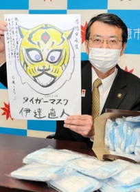 寄贈されたマスクを前にタイガーマスクの似顔絵を持つ牟礼正稔市長＝赤穂市役所