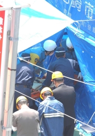 運び出された乗客の遺体に手を合わせる関係者ら（手前）＝尼崎市久々知３