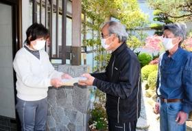 １０万円入りの封筒を各世帯に配る神種自治会の役員ら＝２９日午後、姫路市夢前町神種