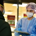 神戸市医師会の急病診療所入り口で待機する防護服姿の看護師＝３月３０日午後、神戸市中央区橘通４（撮影・秋山亮太）