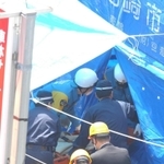 運び出された乗客の遺体に手を合わせる関係者ら（手前）＝尼崎市久々知３