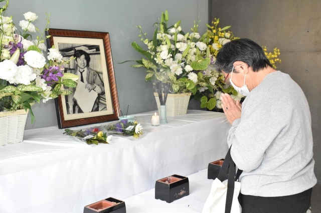 小尻知博記者の遺影に手を合わせる女性。今年は資料室の一般公開は中止された＝西宮市与古道町