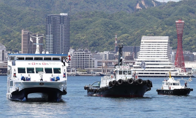 医療従事者を激励しようと、船上から旗を振る船員ら＝８日正午ごろ、神戸市中央区のポートアイランド沖（撮影・辰巳直之）