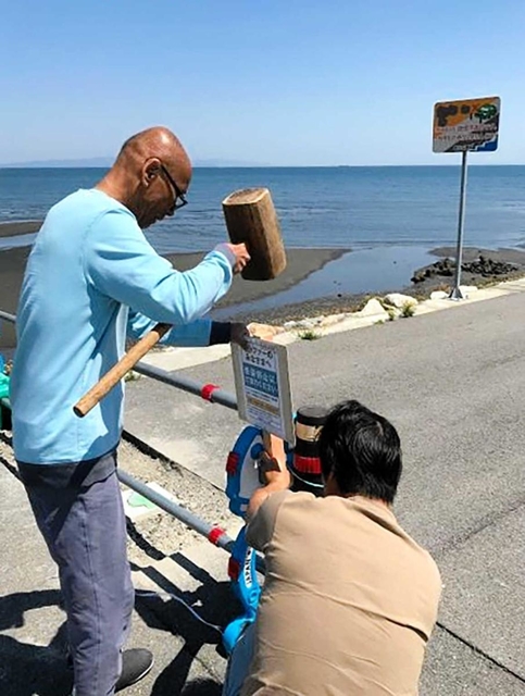 サーフィンの自粛を呼び掛ける張り紙を設置する徳島県サーフィン連盟のメンバー＝徳島県阿南市内（武知さん提供）