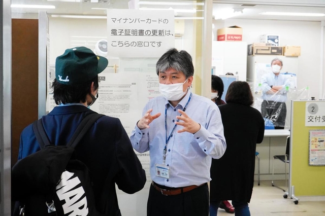 来庁者に対し、マイナンバーカードのシステムがダウンしたことを説明する市職員＝午前９時５６分、尼崎市役所