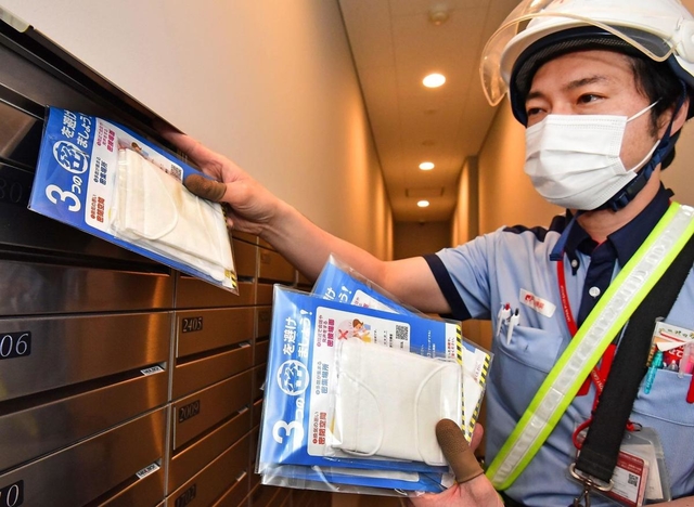 マンションの郵便受けにマスクを入れていく配達員＝１３日午後、神戸市中央区（撮影・秋山亮太）