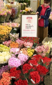 「母の月」をＰＲするポスターが掲げられた生花仲卸店。色とりどりのカーネーションが並ぶ＝姫路市御国野町、姫路生花卸売市場