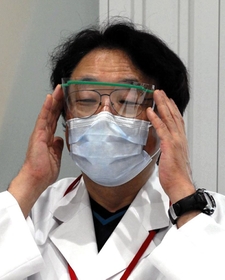 職員が使う眼鏡型のプラスチック防具を着ける栗本院長＝神戸市中央区港島南町２、神戸アイセンター病院