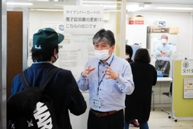 来庁者に対し、マイナンバーカードのシステムがダウンしたことを説明する市職員＝午前９時５６分、尼崎市役所