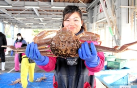 ３月２０日に行われた今季最終競りで水揚げしたマツバガニを掲げる船員家族＝兵庫県香美町香住区沖浦、柴山港
