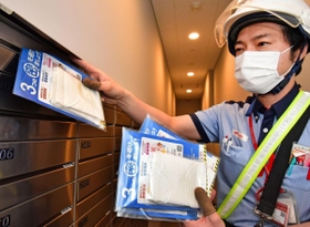 マンションの郵便受けにマスクを入れていく配達員＝１３日午後、神戸市中央区（撮影・秋山亮太）