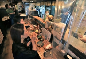 感染予防のためカウンター席にビニールシートを設置した店内で飲食を楽しむ常連客ら＝２３日夜、神戸市兵庫区羽坂通３（撮影・斎藤雅志）