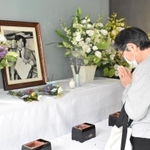 小尻知博記者の遺影に手を合わせる女性。今年は資料室の一般公開は中止された＝西宮市与古道町