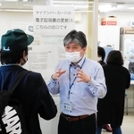 来庁者に対し、マイナンバーカードのシステムがダウンしたことを説明する市職員＝午前９時５６分、尼崎市役所