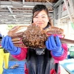 ３月２０日に行われた今季最終競りで水揚げしたマツバガニを掲げる船員家族＝兵庫県香美町香住区沖浦、柴山港