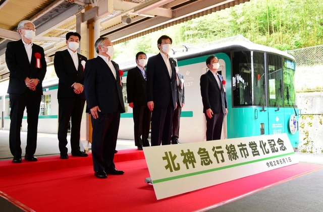 市営化を記念した臨時電車の前で記念撮影する久元喜造神戸市長（前列右から２人目）ら＝１日午前、神戸市北区、谷上駅（撮影・中西幸大）