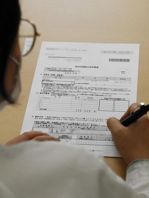 特別定額給付金の申請書に署名する技能実習生＝兵庫県福崎町内（画像の一部を加工しています）