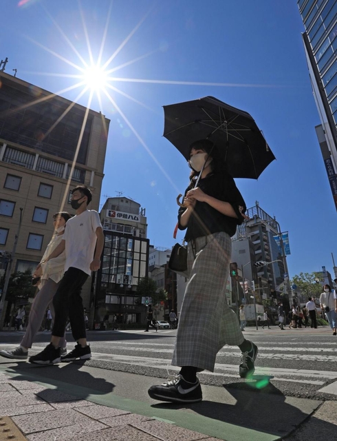 強い日差しの下、日傘を差して歩く人ら＝８日午後、神戸・元町