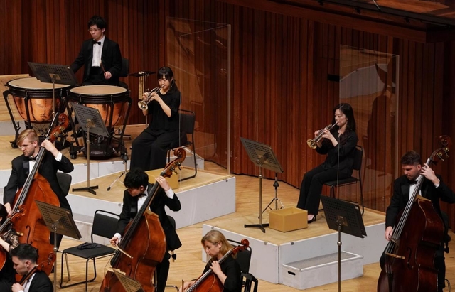 透明なアクリル板を設置したり、隣との距離を空けて座ったりして感染予防をしながら演奏する団員ら＝１９日午後、西宮市高松町２、兵庫県立芸術文化センター（撮影・斎藤雅志）