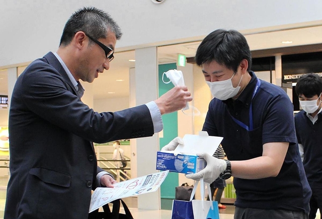空港の利用者にマスク着用を呼び掛ける関西エアポートのスタッフ（右）＝神戸空港