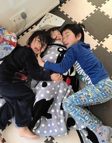 寝起きの煌之介ちゃん（１）＝中央＝を抱き締める信之亮君（６）と愛紗ちゃん（４）