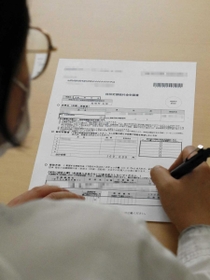 特別定額給付金の申請書に署名する技能実習生＝兵庫県福崎町内（画像の一部を加工しています）