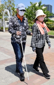 ガイドヘルパー（右）の肘を借りて歩く全盲の福井照久さん＝神戸市中央区