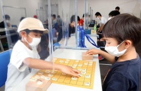 透明のビニールシートを挟んで将棋を楽しむ子どもたち＝加古川市加古川町篠原町