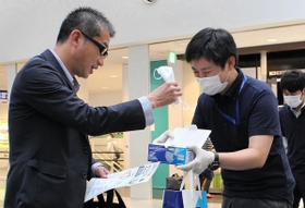 空港の利用者にマスク着用を呼び掛ける関西エアポートのスタッフ（右）＝神戸空港