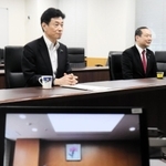 山田錦の産地支援について兵庫県内のＪＡ代表者らとＴＶ会議で意見交換する西村康稔経済再生担当相（左）と山田比早之衆院議員＝内閣府