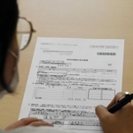 特別定額給付金の申請書に署名する技能実習生＝兵庫県福崎町内（画像の一部を加工しています）