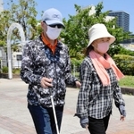 ガイドヘルパー（右）の肘を借りて歩く全盲の福井照久さん＝神戸市中央区
