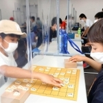 透明のビニールシートを挟んで将棋を楽しむ子どもたち＝加古川市加古川町篠原町