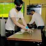 開店前に店内を清掃する店員。机にはコロナ対策を伝えるパネルを置く＝神戸市中央区中山手通１、スポーツバー「ディーフェンス」